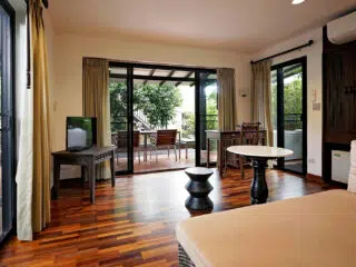 Jasny salon z drewnianą podłogą, sofą i widokiem na patio - idealny po wyjeździe kitesurfingowym z KiteAway lub planowaniu obozu kitesurfingowego.