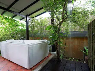 Biała wanna na tarasie w otoczeniu zieleni-idealna na relaks po kursie kitesurfingu lub wyjazdach kitesurfingowych z KiteAway.