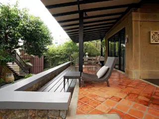 Przytulny taras z leżakiem i ławką, idealny na relaks po kite campie z KiteAway; zielone rośliny, wakacje z kitesurfingiem.