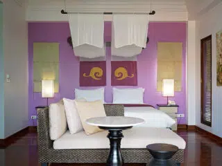 Nowoczesna sypialnia KiteAway z fioletową ścianą, dekoracjami i wygodnym łóżkiem-idealna po wyjazdach kitesurfingowych.