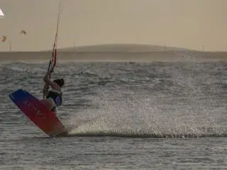 Kiteboarder na oceanie w promieniach słońca, wokół innych kitesurferzy. Idealny kite trip z KiteAway - wyjazdy kitesurfingowe.