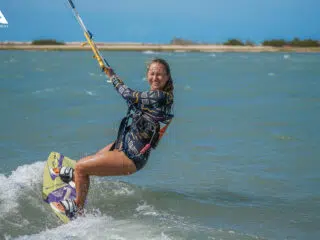 Uśmiechnięta kobieta pływa na kite w piance - szkolenie kitesurfingowe KiteAway, wyjazdy kitesurfingowe, kite camp.