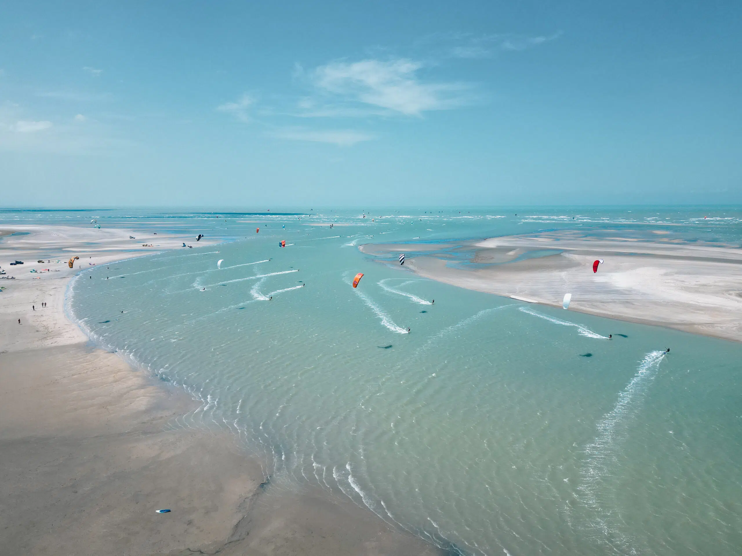 Szeroka plaża z turkusową wodą i sandbankami; kurs kitesurfingu KiteAway, kolorowe latawce, wakacje z kitesurfingiem.