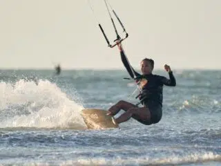 Kitesurfer na fali z latawcem pod błękitnym niebem - idealny wyjazd kitesurfingowy KiteAway, wakacje z kitesurfingiem.