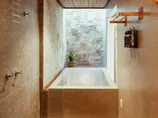 Nowoczesna łazienka z betonową wanną, kamiennymi ścianami i światłem jak na kite camp KiteAway - idealna po wyjazdach kitesurfingowych.