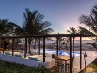 Tropikalny salon przy basenie z widokiem na plażę o zachodzie słońca, idealny relaks po kite campie z KiteAway - wakacje z kitesurfingiem.