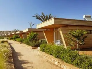 Nowoczesne domki kite camp przy piaszczystej ścieżce i palmach - idealna baza na wyjazdy kitesurfingowe z KiteAway.