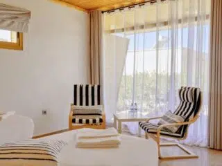 Nowoczesny, jasny pokój z dużym oknem i dwoma fotelami, idealny na relaks po kite campie KiteAway; świetny na wyjazdy kitesurfingowe.