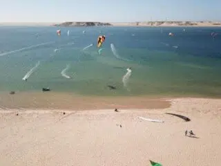 Słoneczna plaża, kolorowi kitesurferzy na turkusowym morzu - idealny spot na wyjazdy kitesurfingowe z KiteAway.