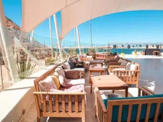 Taras z drewnianymi stołami pod białym zadaszeniem, widok na morze-idealny na relaks po szkoleniu kite lub kite camp KiteAway.