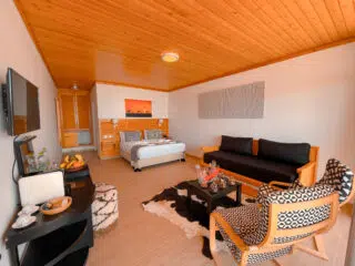 Przytulny pokój KiteAway z drewnianym sufitem po dniu na kite camp; wygodne łóżko, sofa i światło na wakacje z kitesurfingiem.