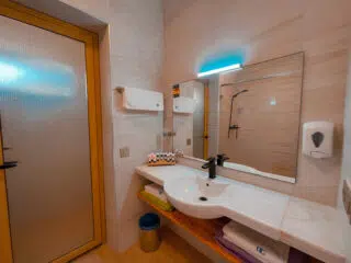 Nowoczesna łazienka idealna na relaks po kursie kitesurfingu lub kite camp z KiteAway. Ręczniki ułożone pod dużą umywalką.