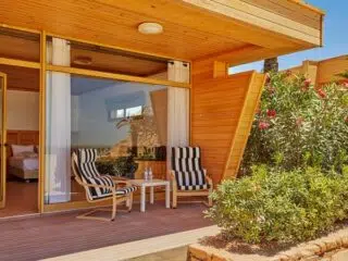 Drewniany bungalow z patio i widokiem na ogród, idealny na relaks po dniu pełnym emocji na wyjeździe kitesurfingowym KiteAway.