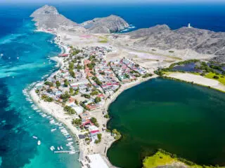Widok na kolorowe miasteczko i lagunę - idealny spot na wakacje z kitesurfingiem z KiteAway, otoczony turkusową wodą.