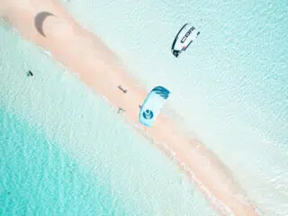 Dwóch kitesurferów na lazurowych wodach przy piaszczystej plaży - idealny kite trip z KiteAway, wakacje z kitesurfingiem.