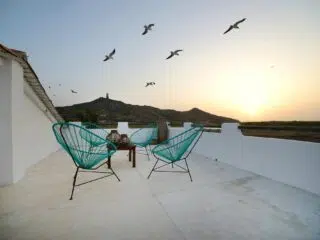 Taras na dachu z turkusowymi krzesłami i stolikiem - idealny relaks po kursie kitesurfingu lub kite camp z KiteAway.pl.