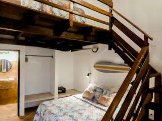 Przytulny pokój KiteAway z łóżkiem piętrowym, deską kite i kwiatową pościelą - idealny na wyjazdy kitesurfingowe i kite camp.