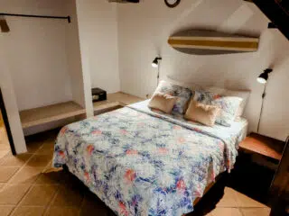 Przytulna sypialnia z podwójnym łóżkiem i motywem surfingu, idealna na relaks po dniu pełnym wrażeń na wyjeździe kitesurfingowym.