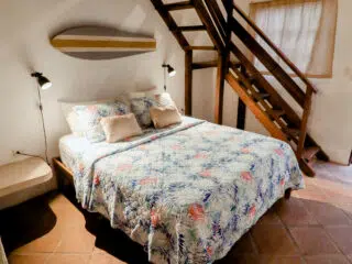 Przytulna sypialnia KiteAway - podwójne łóżko, tropikalna narzuta, schody na antresolę. Idealne po wyjeździe kitesurfingowym.