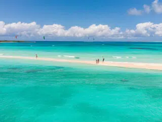 Lotniczy widok na kite spot: turkusowe morze, piaszczysta łacha i kitesurferzy na wakacjach z kitesurfingiem KiteAway.