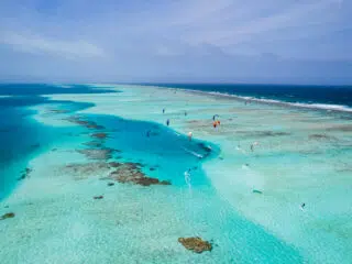 Widok z lotu ptaka na turkusową lagunę z kitesurferami, czysta woda, rafy koralowe - idealne miejsce na wyjazdy kitesurfingowe z KiteAway.