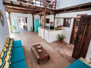 Jasny salon z sofą i poduszkami, rustykalne dekoracje, rośliny - idealne miejsce na relaks po kite camp z KiteAway.