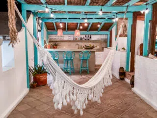 Przytulny taras z białym hamakiem i turkusowymi stolikami, idealny na relaks po kursie kitesurfingu z KiteAway lub kite camp.