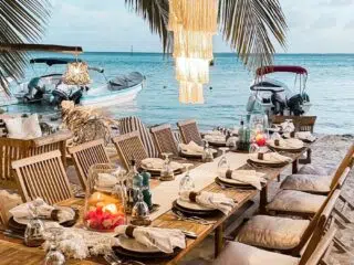 Długi, elegancko nakryty stół na plaży po dniu wyjazdów kitesurfingowych KiteAway, lampiony, łodzie, zachód słońca, palmy.