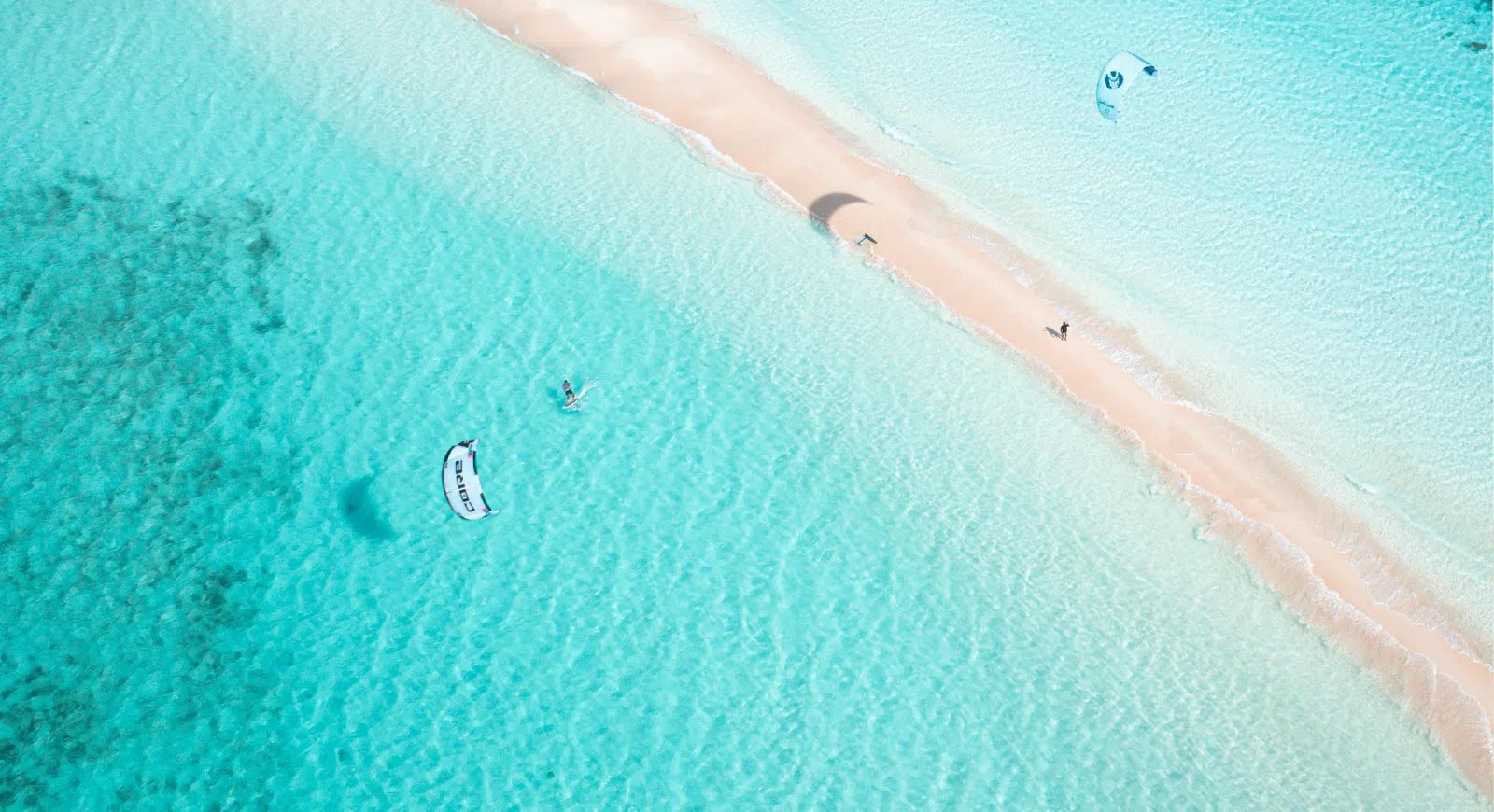 Dwóch kitesurferów nad turkusową wodą i mielizną podczas kite trip KiteAway - idealne wyjazdy kitesurfingowe, wakacje z latawcem.