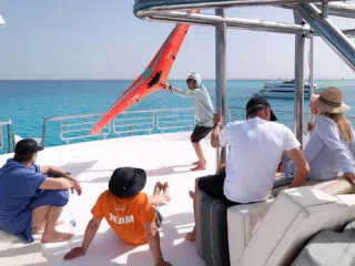 Grupa na jachcie podczas wyjazdu KiteAway; relaks na pokładzie, widok na wodę, sprzęt kite, idealne wakacje z kitesurfingiem.