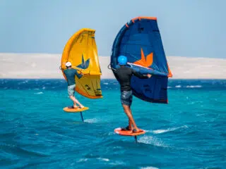 Dwóch riderów na wing foilu blisko brzegu, idealne warunki na kurs kitesurfingu lub kite camp z KiteAway - wyjazdy kitesurfingowe.