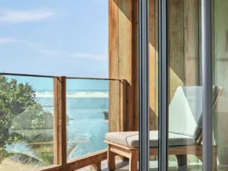 Balkon z widokiem na morze i drzewa, idealny na relaks po szkoleniu kite - wymarzone wakacje z kitesurfingiem z KiteAway.