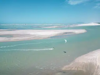 Kitesurfer płynie po lazurowej wodzie na kite camp KiteAway; idealne miejsce na wyjazdy kitesurfingowe i wakacje z kitesurfingiem.