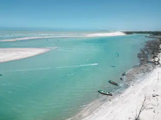 Turkusowa plaża z łachami piasku, łodziami i kitesurferami-idealny spot kite na wyjazdy kitesurfingowe z KiteAway.
