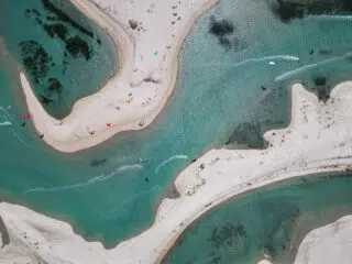 Widok z lotu ptaka na kręte piaszczyste łachy i turkusową wodę - idealne miejsce na wyjazdy kitesurfingowe z KiteAway.