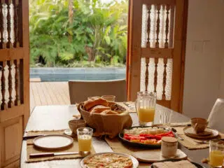 Stół śniadaniowy z pieczywem i kawą przy basenie, idealny początek dnia na wyjazdy kitesurfingowe z KiteAway.