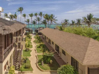 Ośrodek z palmami i ogrodami nad oceanem, idealny na kite camp lub wyjazdy kitesurfingowe z KiteAway pod błękitnym niebem.