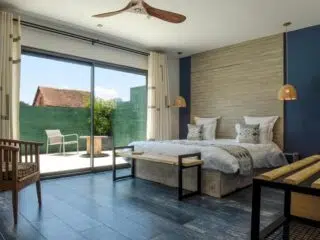 Nowoczesna sypialnia z dużym łóżkiem po udanym wyjeździe kitesurfingowym KiteAway; widok na słoneczny taras i relaks.