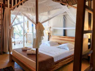 Przytulna sypialnia z baldachimem, idealna na relaks po kite camp z KiteAway; słońce tworzy wakacyjny klimat kitesurfingu.