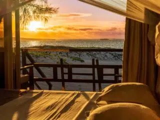 Widok z łóżka na plażę i spokojne morze o zachodzie słońca-idealne miejsce na wyjazdy kitesurfingowe z KiteAway.