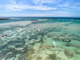Laguna o turkusowej wodzie, kolorowi kitesurferzy na kursie kitesurfingu z KiteAway. Idealny spot na wyjazdy kitesurfingowe.