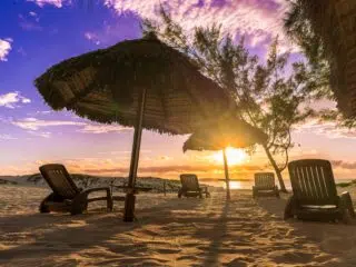 Leżaki pod parasolami na plaży o zachodzie słońca, idealne po dniu na kite campie z KiteAway - wyjazdy kitesurfingowe.