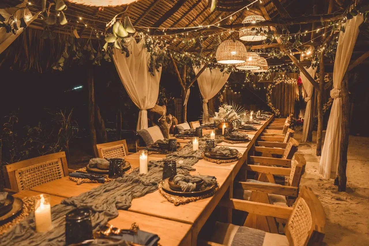 Długi, drewniany stół na wieczór po kite tripie, ze świecami i lampkami, czeka na uczestników wyjazdów kitesurfingowych KiteAway.