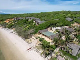 Rustykalne bungalowy w zieleni przy plaży, idealne na wyjazdy kitesurfingowe z KiteAway; palmowy kite spot, turkusowa woda.