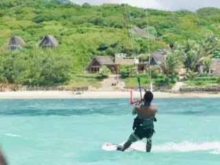 Kitesurfer na turkusowej wodzie przy piaszczystej plaży - idealne miejsce na wyjazdy kitesurfingowe z KiteAway.