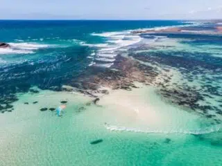 Lotniczy widok na turkusowe morze i kitesurfera przy brzegu - idealny spot na wyjazdy kitesurfingowe z KiteAway.