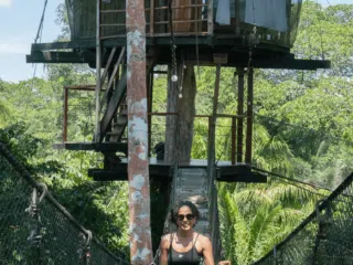 Uśmiechnięta kobieta na mostku linowym symbolizuje energię i pasję uczestników wyjazdów kitesurfingowych KiteAway.