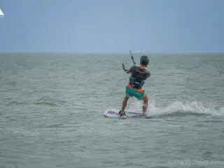 Kitesurfer w kasku i trapezie sunie po spokojnym morzu; idealny spot na wyjazdy kitesurfingowe z KiteAway.