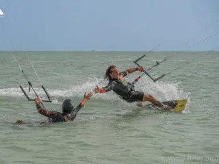 Dwie osoby podczas kursu kitesurfingu na morzu - jedna pomaga drugiej w wodzie podczas wyjazdu kitesurfingowego z KiteAway.