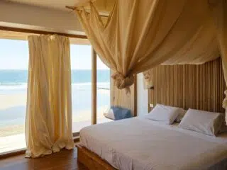 Jasna sypialnia z baldachimem i widokiem na plażę - idealne miejsce na odpoczynek po całym dniu wyjazdu kitesurfingowego z KiteAway.